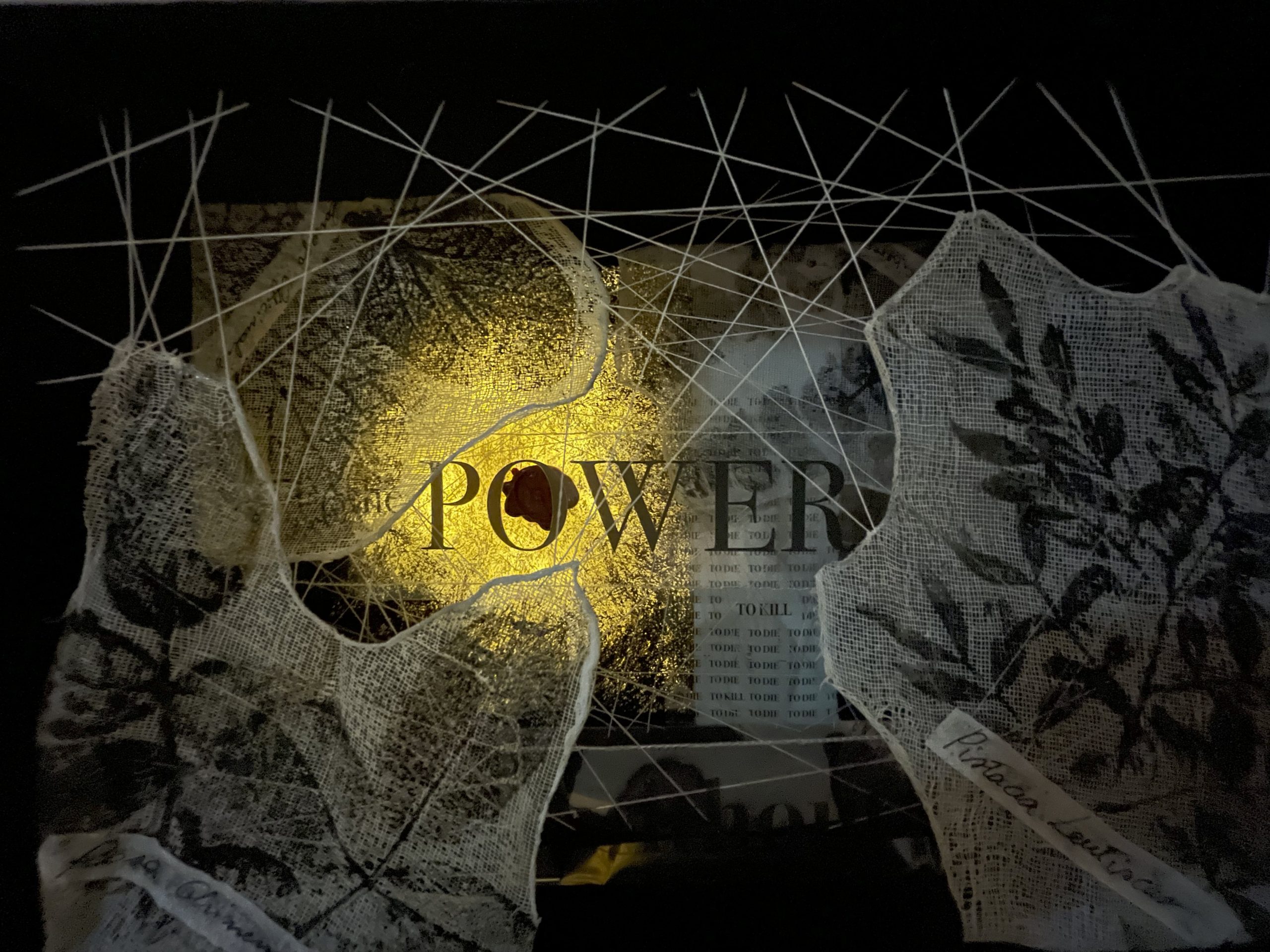 Chest containing a tangle of fabrics, threads, recurring instances of the word Power and flower prints inside.
